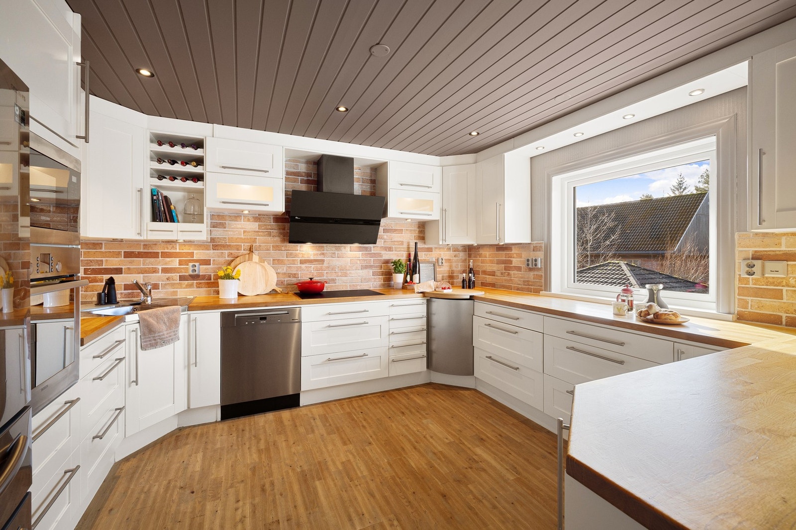 Kjøkkeninnredning med hvite profilerte fronter og benkeplate av heltre. Galleribilde