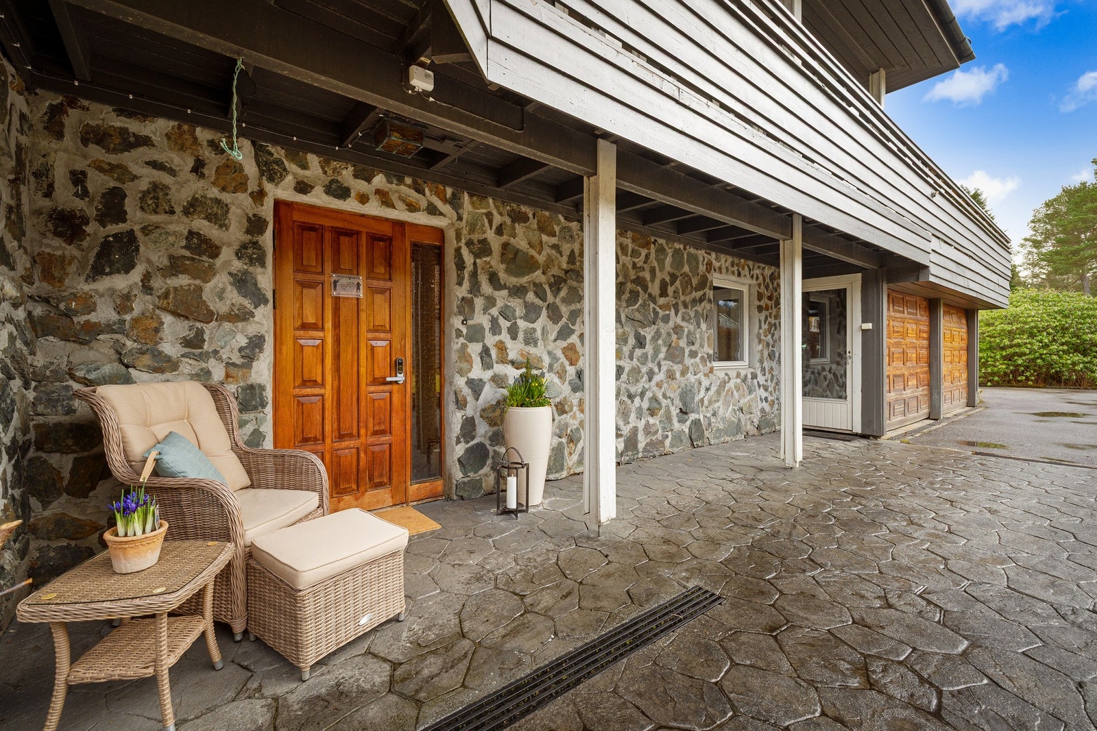 Fint inngangsparti med pressbetong og takoverbygg. Dør inn til garasjen. Galleribilde