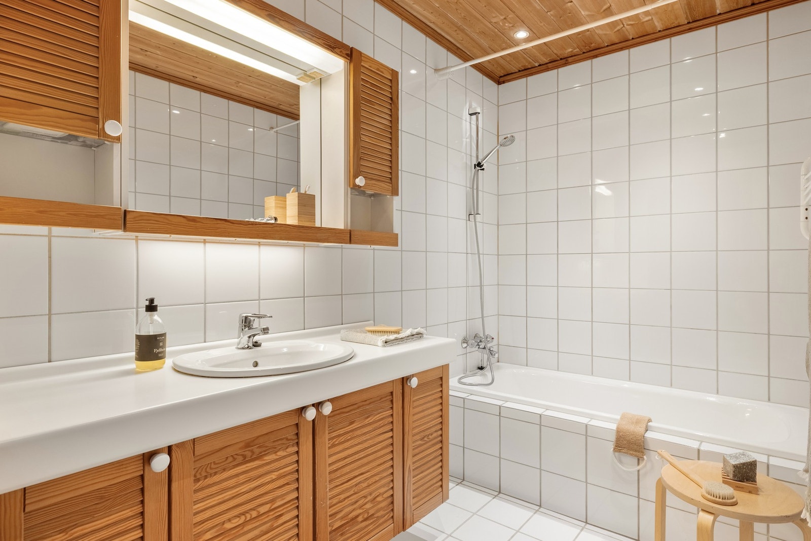 Det er innredet med badekar med dusj og baderomsmøblement med mye oppbevaringsplass, speil og belysning. Galleribilde