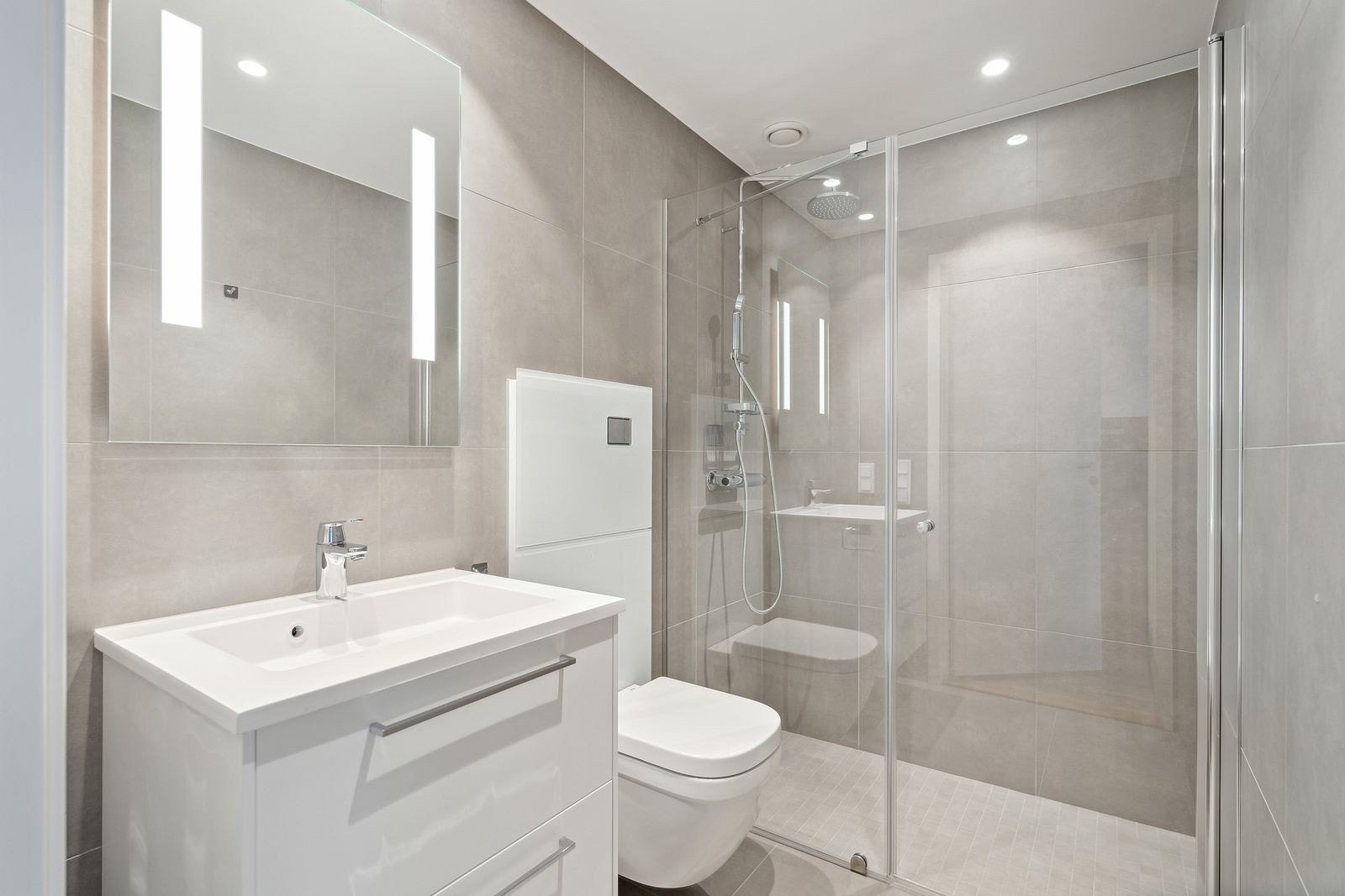 Romslig og flislagt bad med stor dusj.