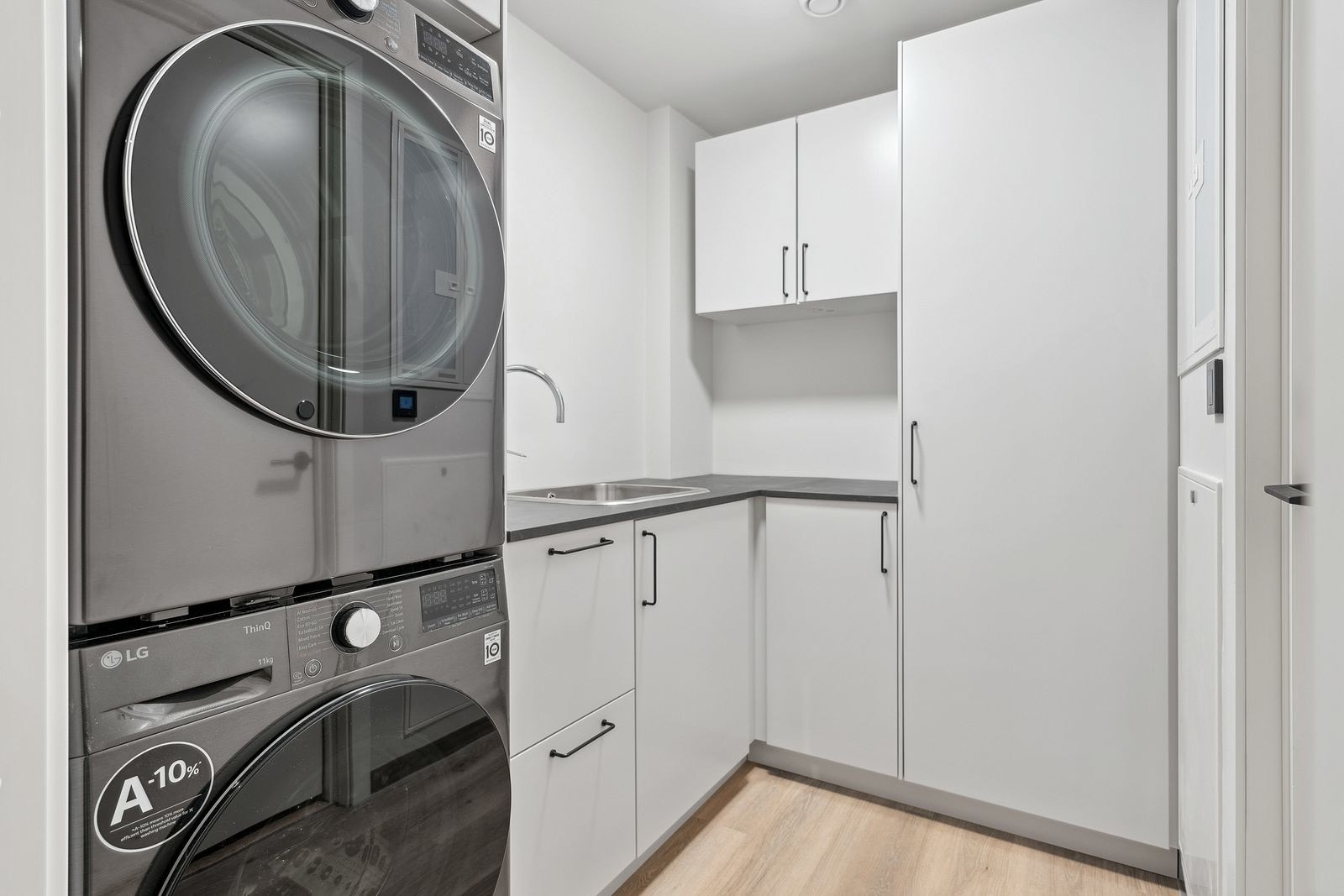 Felles vaskerom utstyrt med vaskemaskin, tørketrommel og rikelig skapplass.