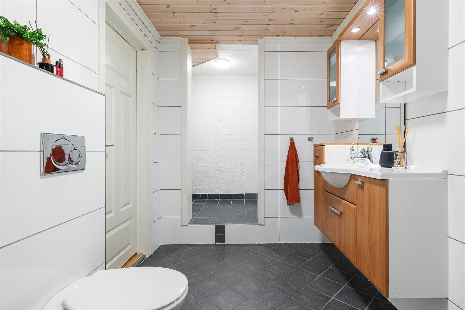 Rommet er innredet med dusjhjørne, vegghengt toalett og romslig baderomsinnredning. Innerst er det en egen vaskeromsavdeling med opplegg for vask og tørk. Galleribilde