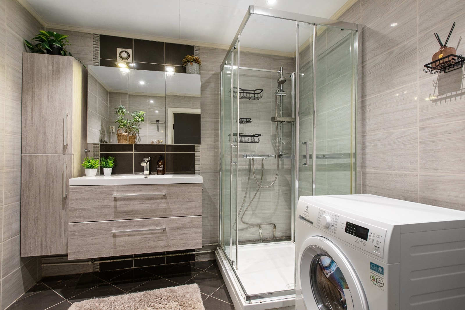 Badet har flislagte vegger og gulv, samt slette overflater i himlingen. Innredningen består av en servant med slette fronter, et dusjkabinett og opplegg for vaskemaskin. Galleribilde