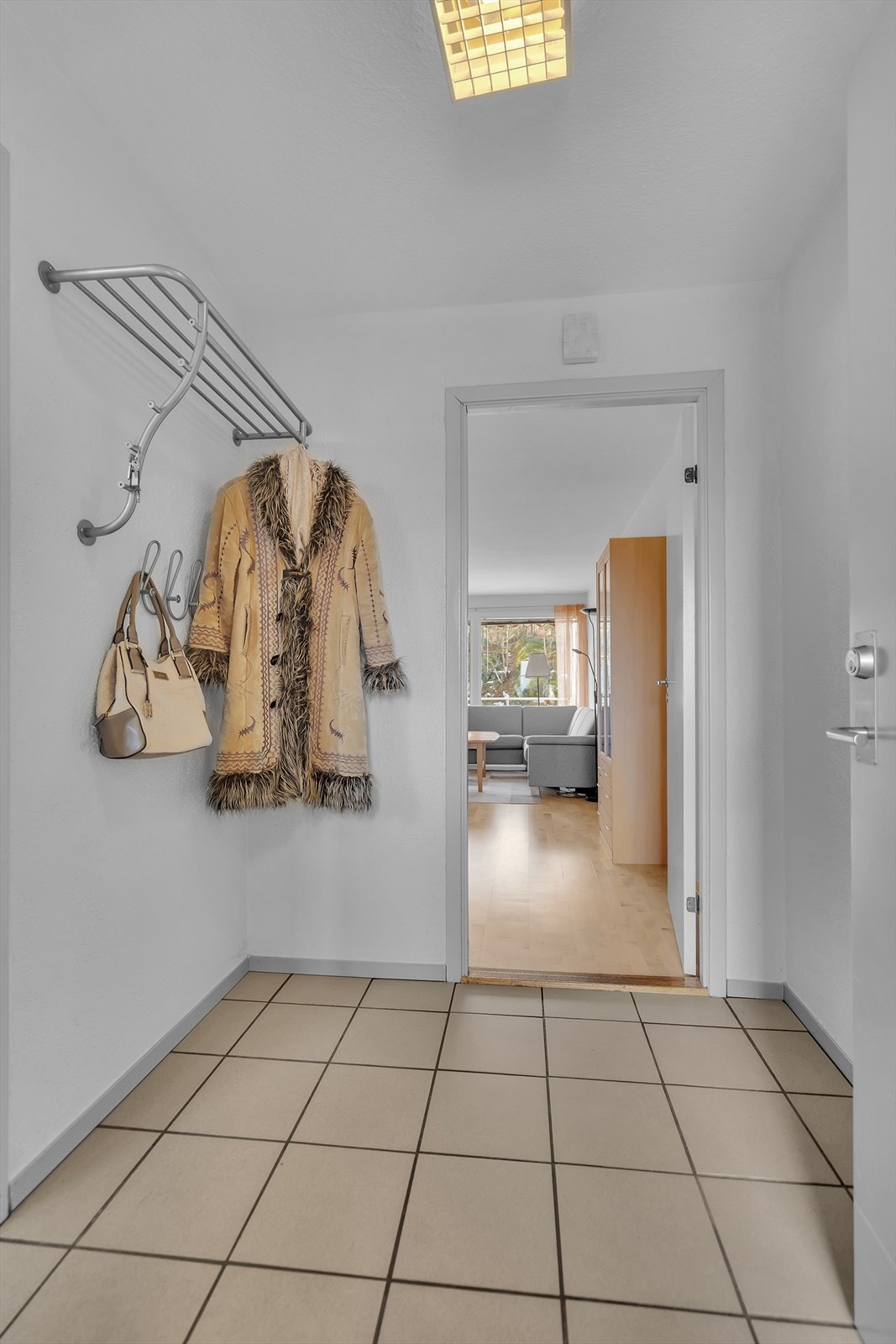 Leiligheten ønsker deg velkommen med en lys og innbydende entré som setter standarden for resten av boligen. Gulvet er belagt med stilrene fliser, som ikke bare gir et elegant uttrykk, men også er en praktisk løsning som tåler daglig bruk. Galleribilde