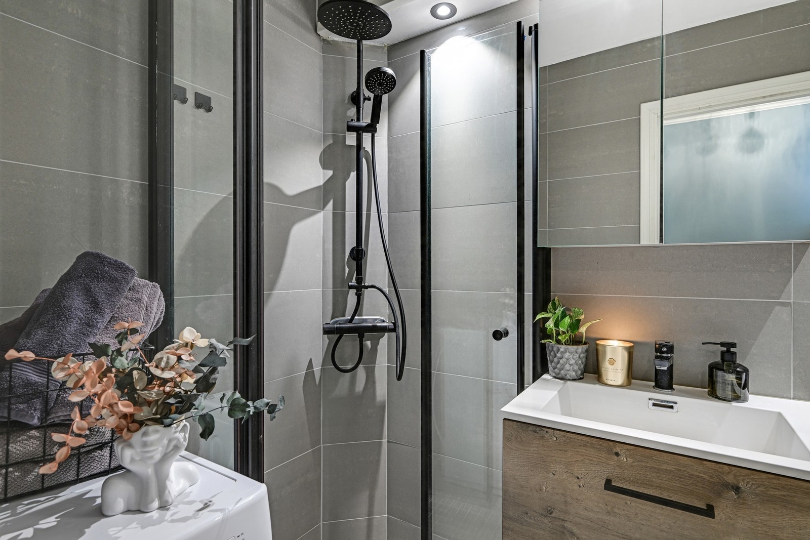 Badet er innredet med praktiske og moderne dusjvegger, pen baderomsinnredning, klosett og opplegg for vaskemaskin. Galleribilde