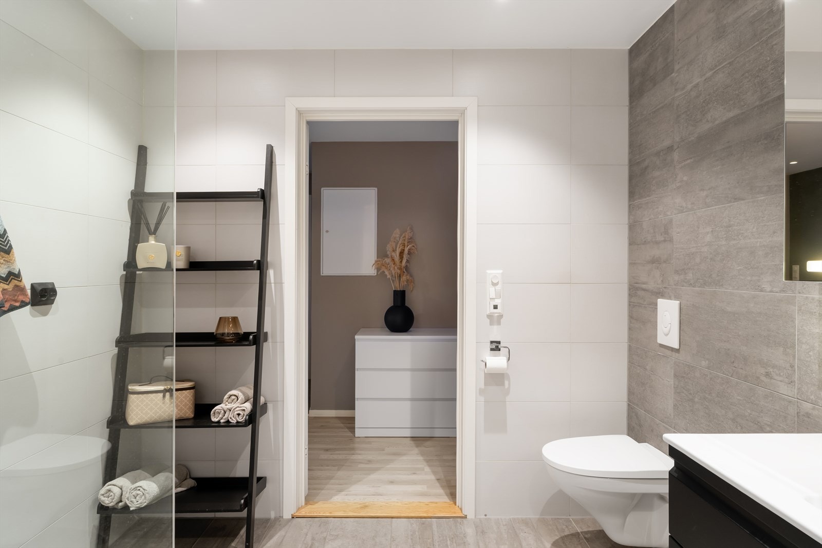 Badet er utstyrt med baderomsinnredning, vegghengt toalett og dusjhjørne med glassvegg, samt innfelte høyttalere i tak. Galleribilde