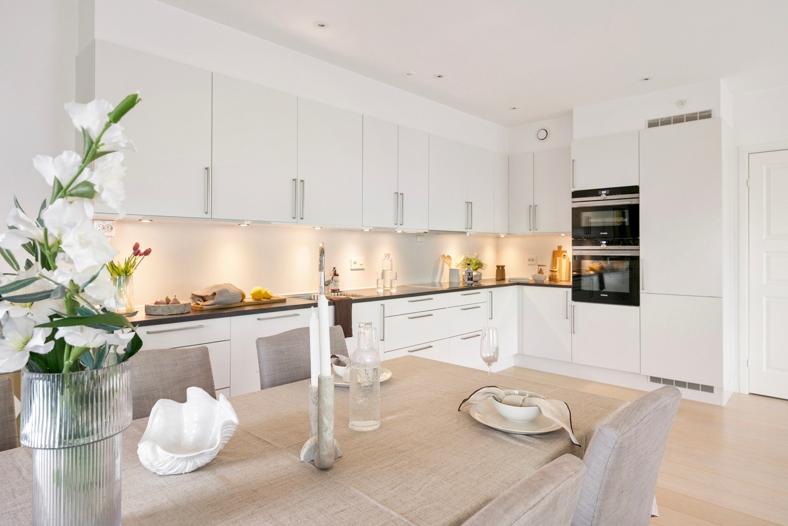 Lyst og fint kjøkken, belysning under overskapene og integrerte hvitevarer Galleribilde