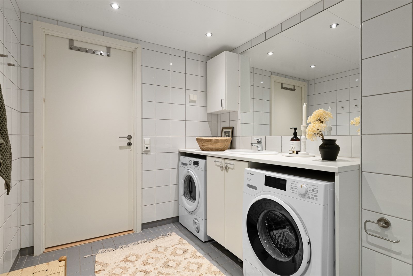 Badet er innredet med en nedfelt servant, overhengende speil og belysning. Dusjen er plassert i hjørnet og har håndholdt dusjarmatur samt dusjvegger. Videre er det montert et vegghengt toalett. Galleribilde