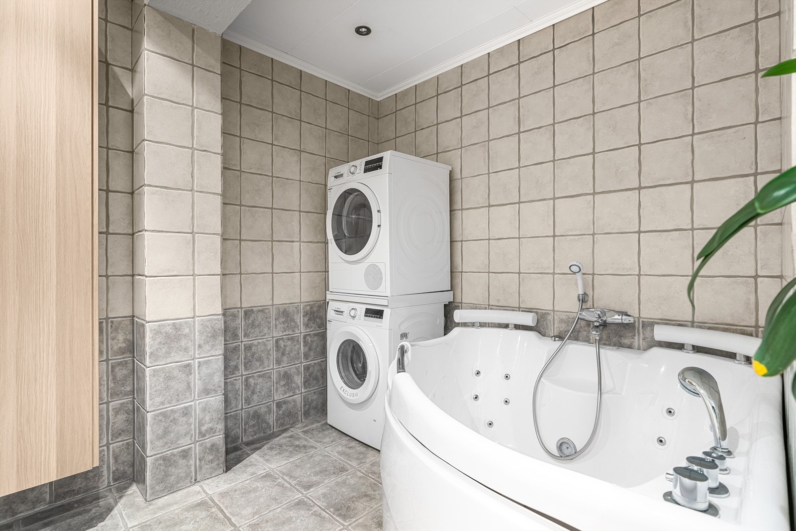 Lyst og delikat flislagt bad med god plass til vaskemaskin og tørketrommel Galleribilde