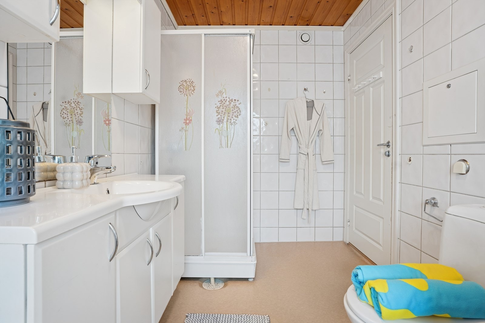 Badet er utstyrt med dusjkabinett, romslig servantinnredning og gulvmontert toalett. Galleribilde