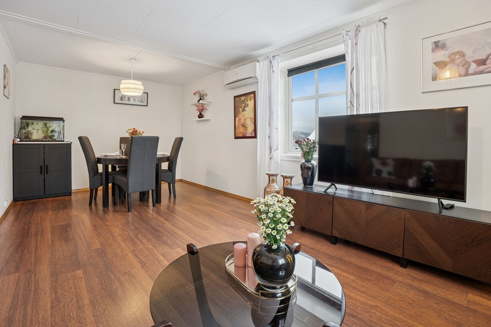 Stuen har god plass til både sofagruppe og spisebord, og oppvarming skjer via panelovner og varmepumpe. Galleribilde