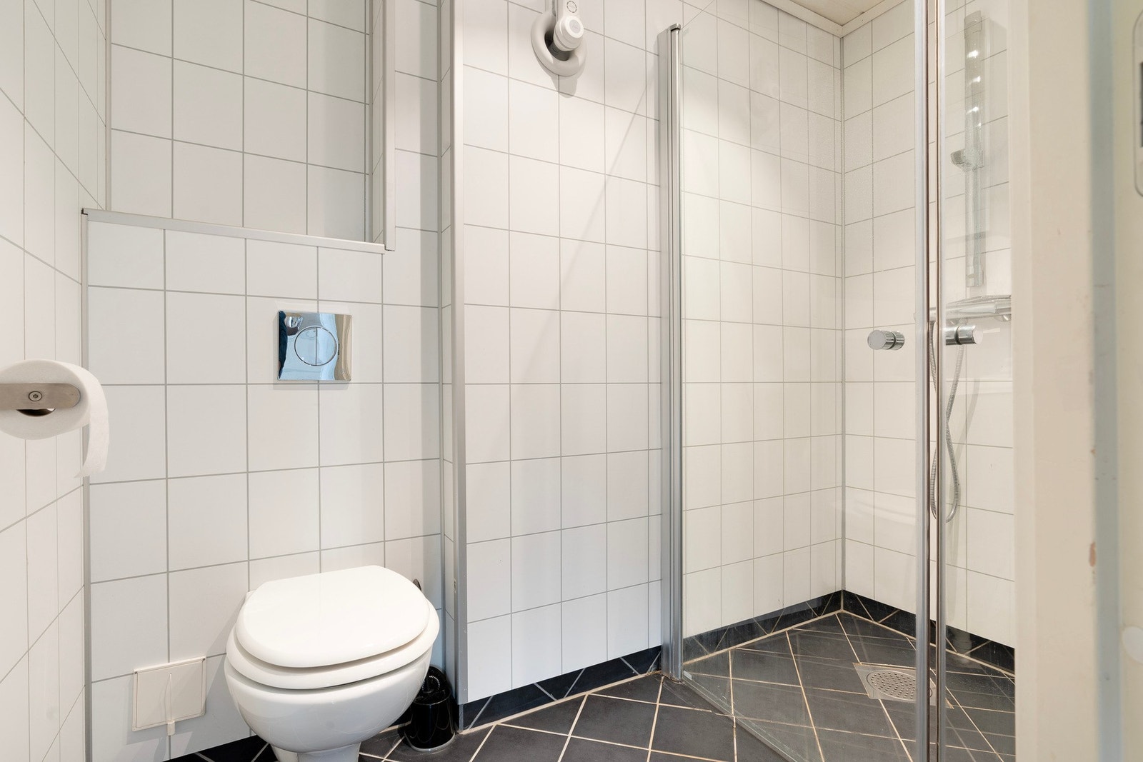 Flislagt bad med dusjhjørne og baderomsinnredning med speilskap Galleribilde