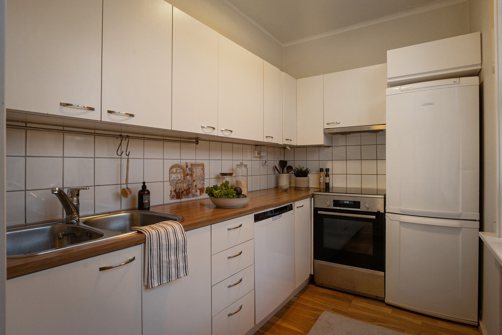 Innredningen har laminat benkeplate med nedfelt oppvaskkum og flislagt backsplash over benk. Galleribilde