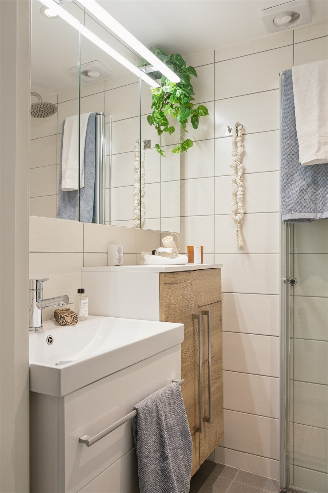 Pent baderom med keramiske fliser på gulv, vegger og malt platekledning med spotlights i himling.
Inneholder: Servant med møblement, vegghengt toalett, innfelbart dusjhjørne i glass og rør i rør skap.
Varmekabler i gulv. Galleribilde