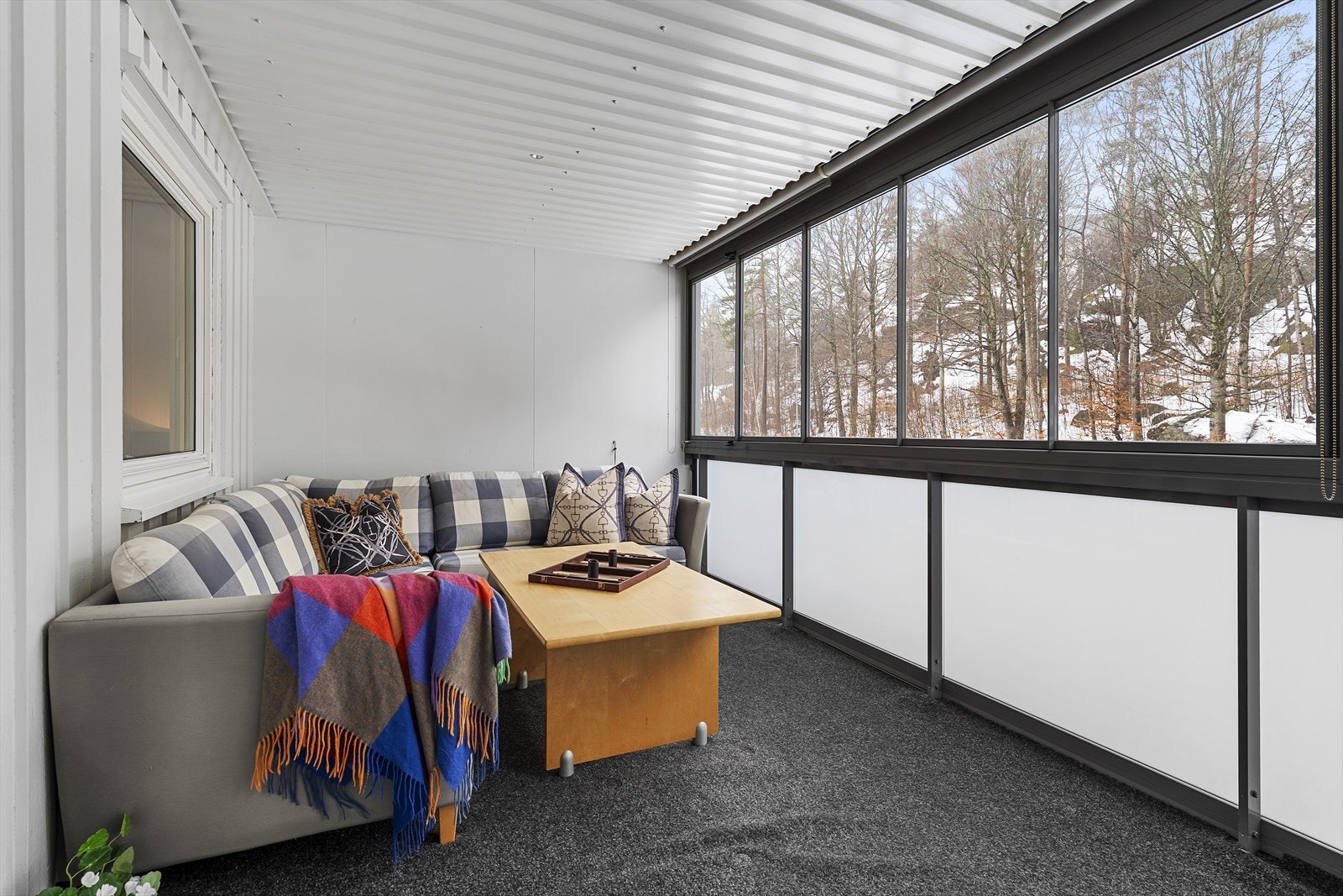 Innglasset balkong med utsyn mot skogholt på den andre siden av veien Galleribilde