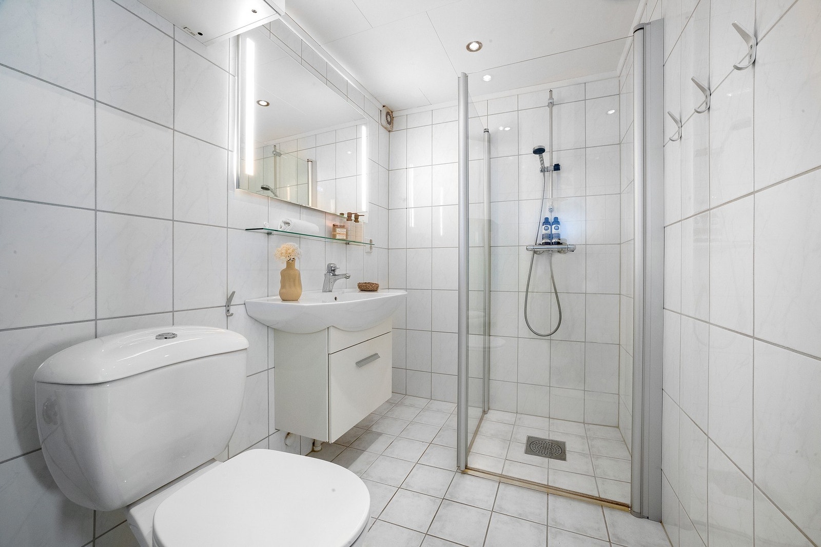 Badet flislagt og har dusjhjørne med innfellbare dusjvegger. Down-lights i himlingen. Galleribilde