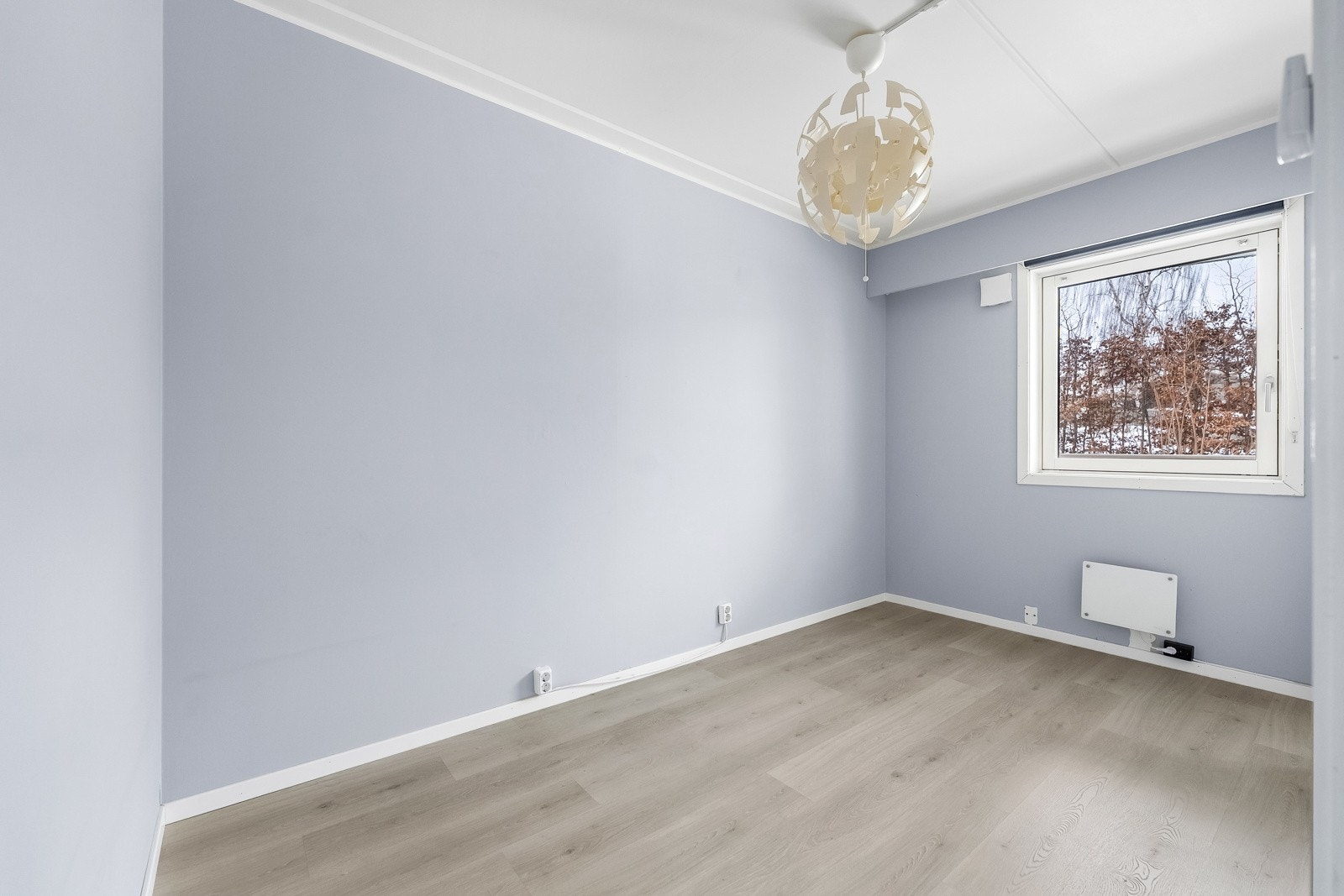 Leiligheten har ett soverom med lysmalte veggflater og lyspigmentert laminat på gulv. Det store vinduet slipper inn rikelig med naturlig lys. Galleribilde