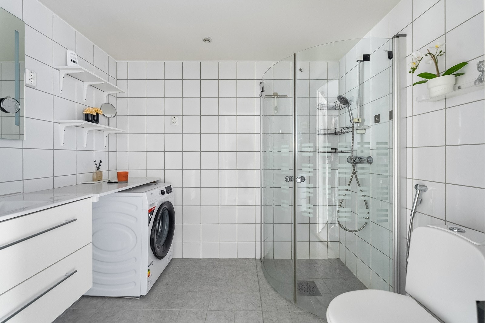 Stort flislagt bad med gulvvarme fra byggeår. Innredningen består av servantmøbel med speil, frittstående toalett og separat dusjhjørne med innfellbare glassdører. Galleribilde