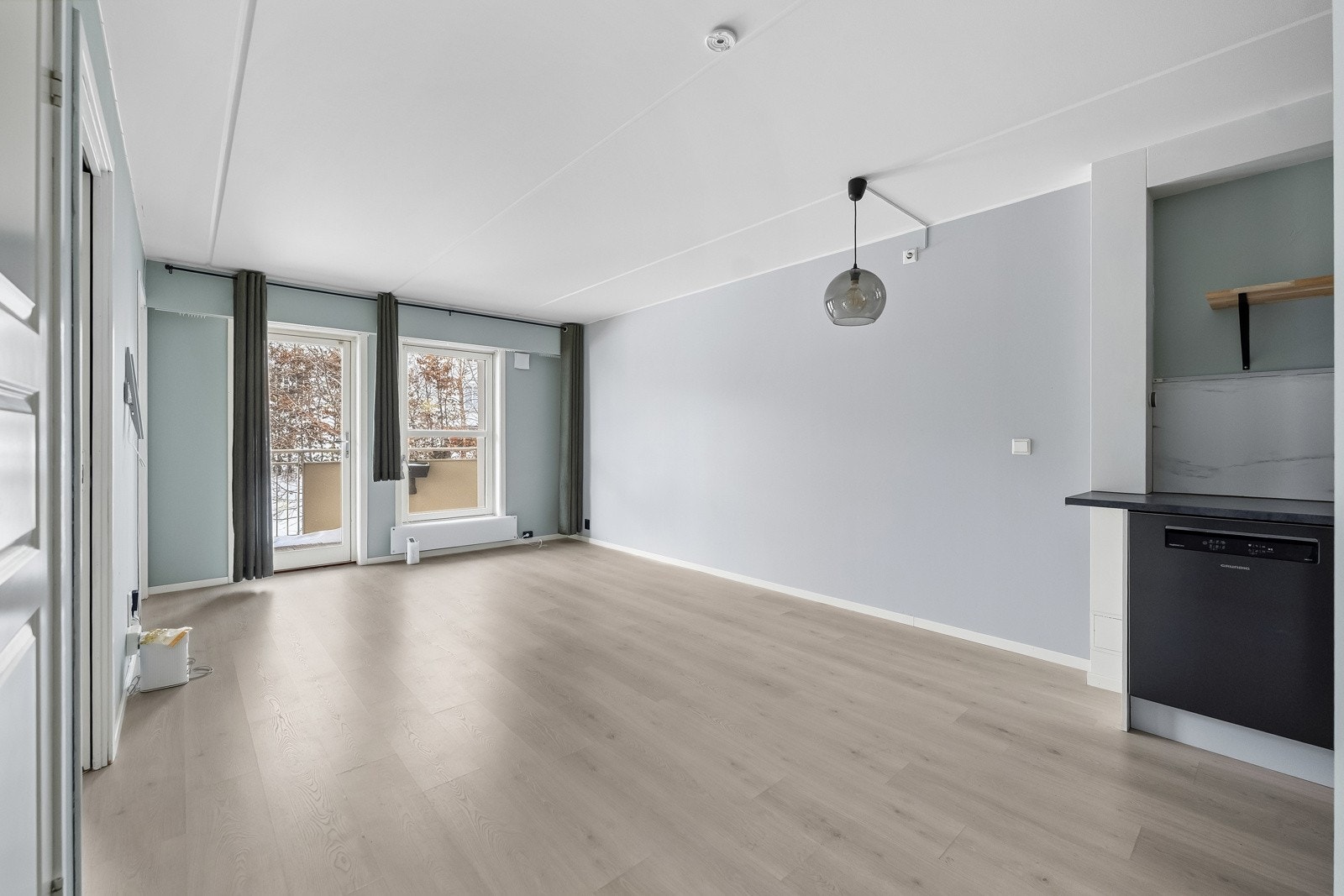 Åpen stue med lysmalte vegger og lyspigmentert laminat på gulv. Store vindusflater slipper inn godt med dagslys og gir en luftig romfølelse. Galleribilde