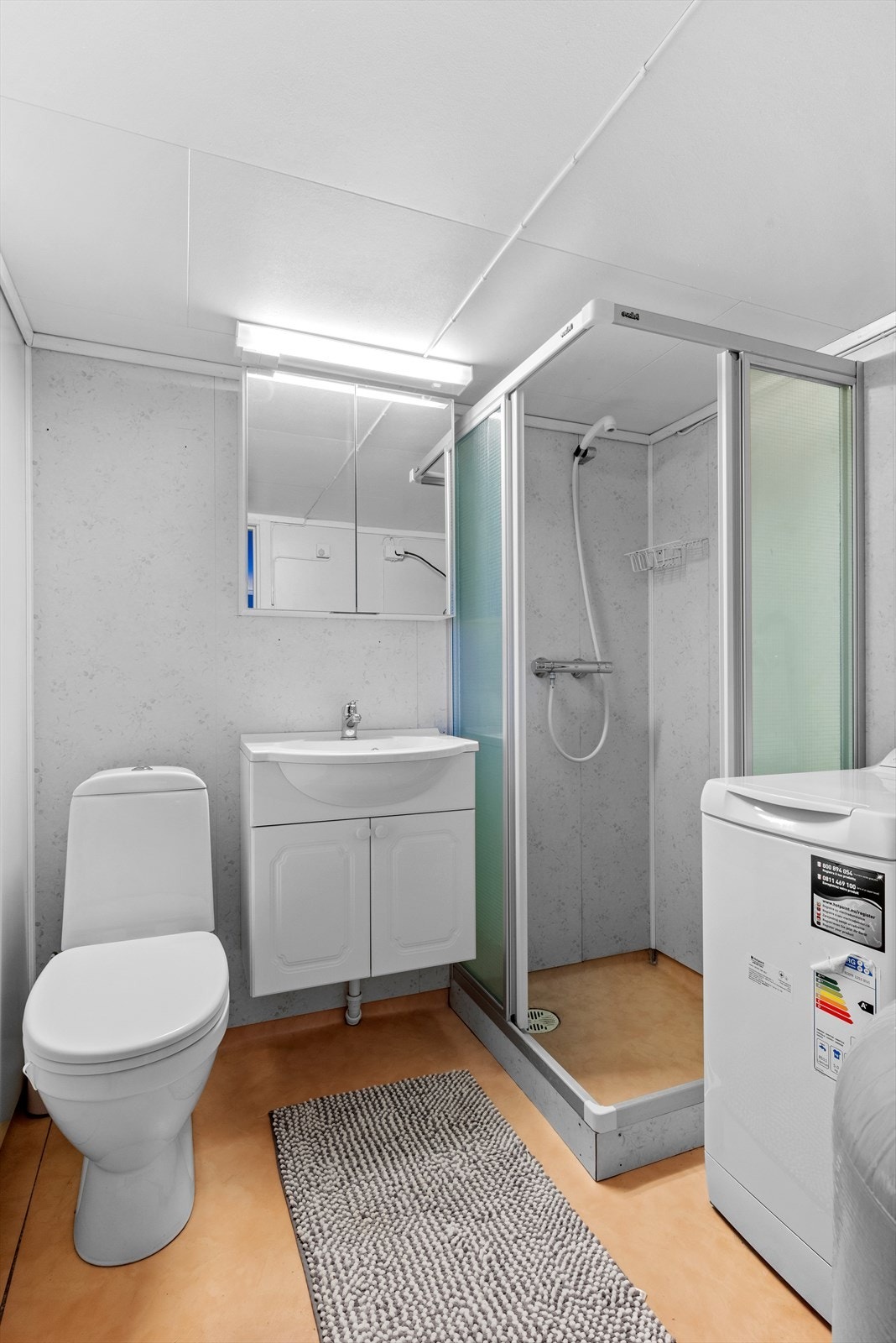 Badet nede er utstyrt med wc, servantskap med heldekkende servant, speilskap, dusjhjørne og opplegg for vaskemaskin. Galleribilde