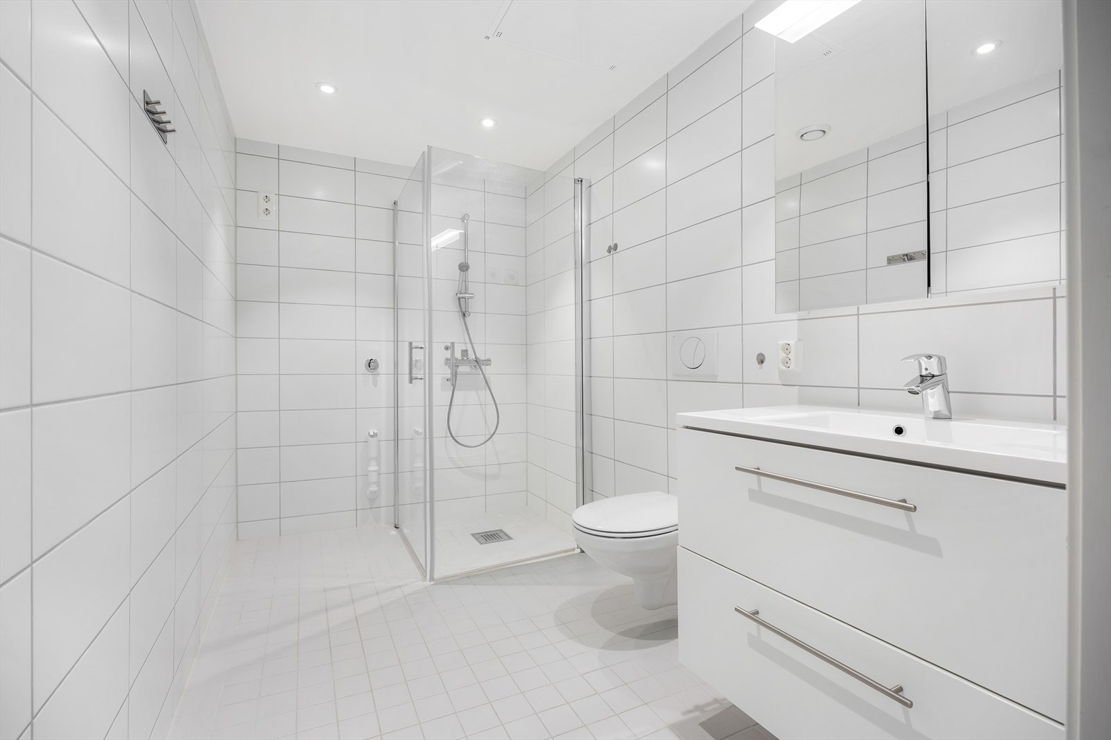 Delikat bad fra 2019 med flislagte overflater, dusjhjørne og vegghengt toalett. Galleribilde