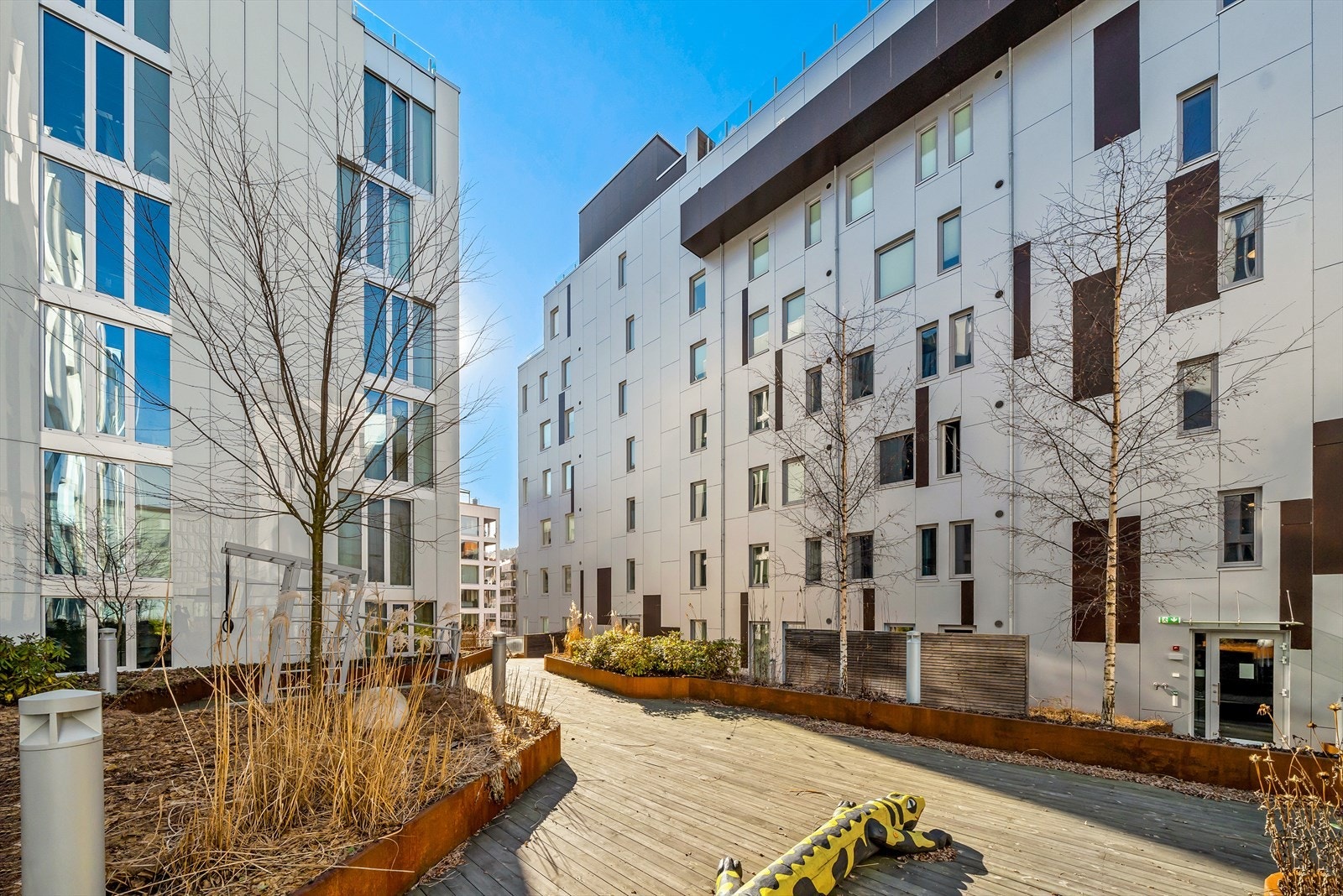 Flere finer soner med beplantning, treningsapparat, sandkasse og barnesone m.m. Galleribilde