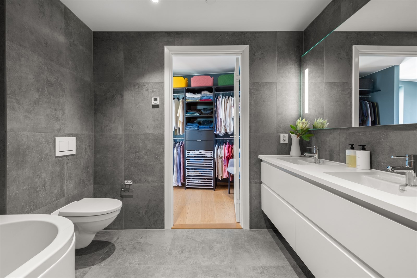 Moderne bad med heldekkende dobbel servant på underskap, speil og god belysning. Vegghengt klosett og dusj med dusjvegger i herdet glass, samt et lukrativt frittstående badekar. Galleribilde