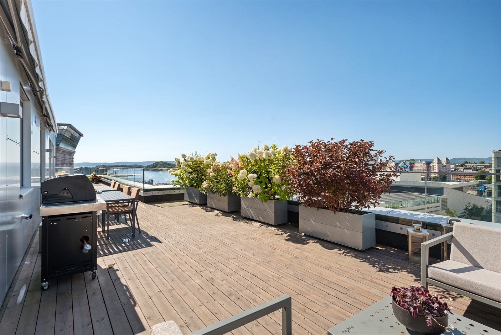 Terrassen strekker seg rundt hjørnet på fasaden, og gir rom for både lounge, spisegruppe og solstoler. Galleribilde