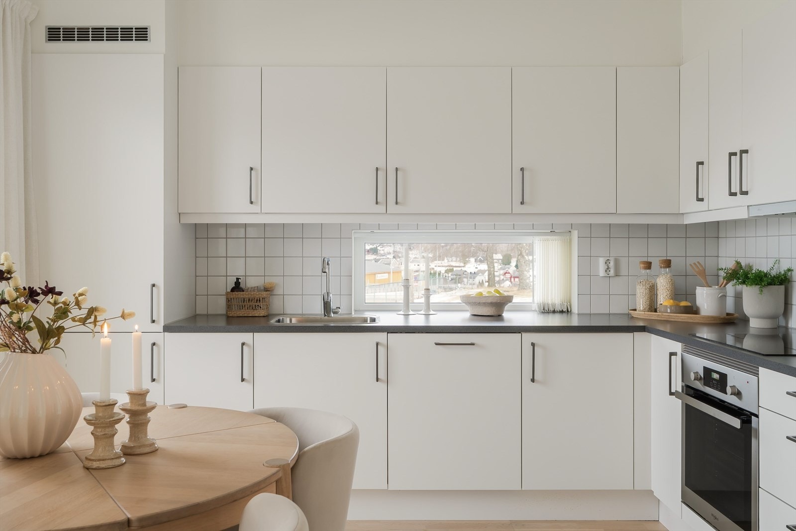 Innredningen har lyse, glatte fronter og koksgrå benkeplate med nedfelt kum. Veggen bak kokesonen og oppvaskkummen er flislagte. Galleribilde