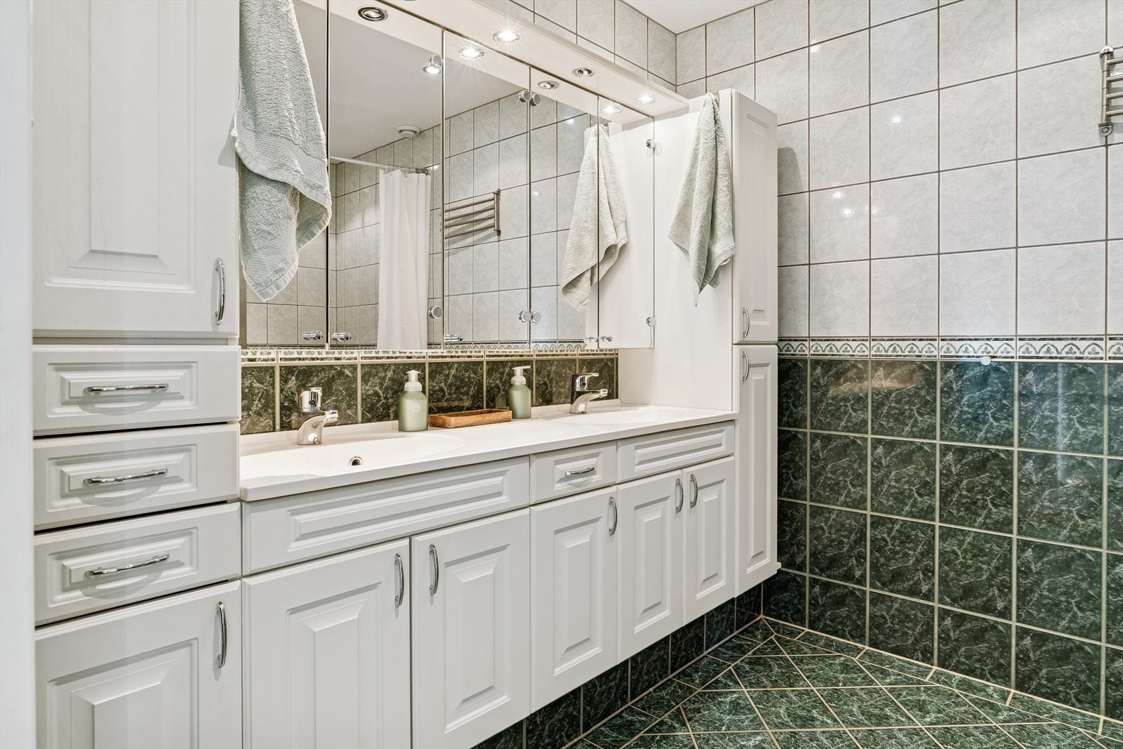 Baderom av god storleik. Her er det også flise på golv og vegg. Romsleg skapinnreiing med heilstøypt, dobbel servant. Speil med overlys i innreiinga. Galleribilde