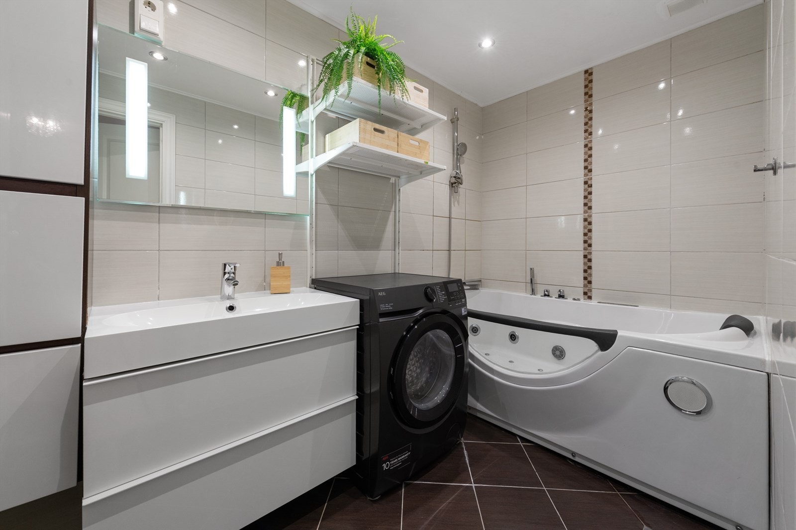 Flislagt bad med badekar og lys og moderne baderomsinnredning Galleribilde