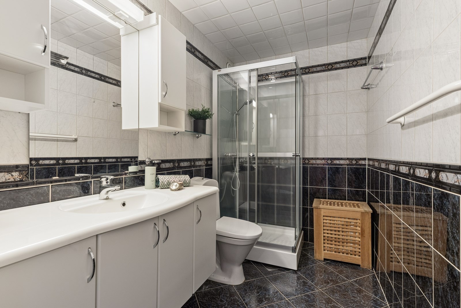 Praktisk bad med flislagt gulv og vegger fra gulv til tak, noe som gir et helhetlig og lettstelt uttrykk. Galleribilde