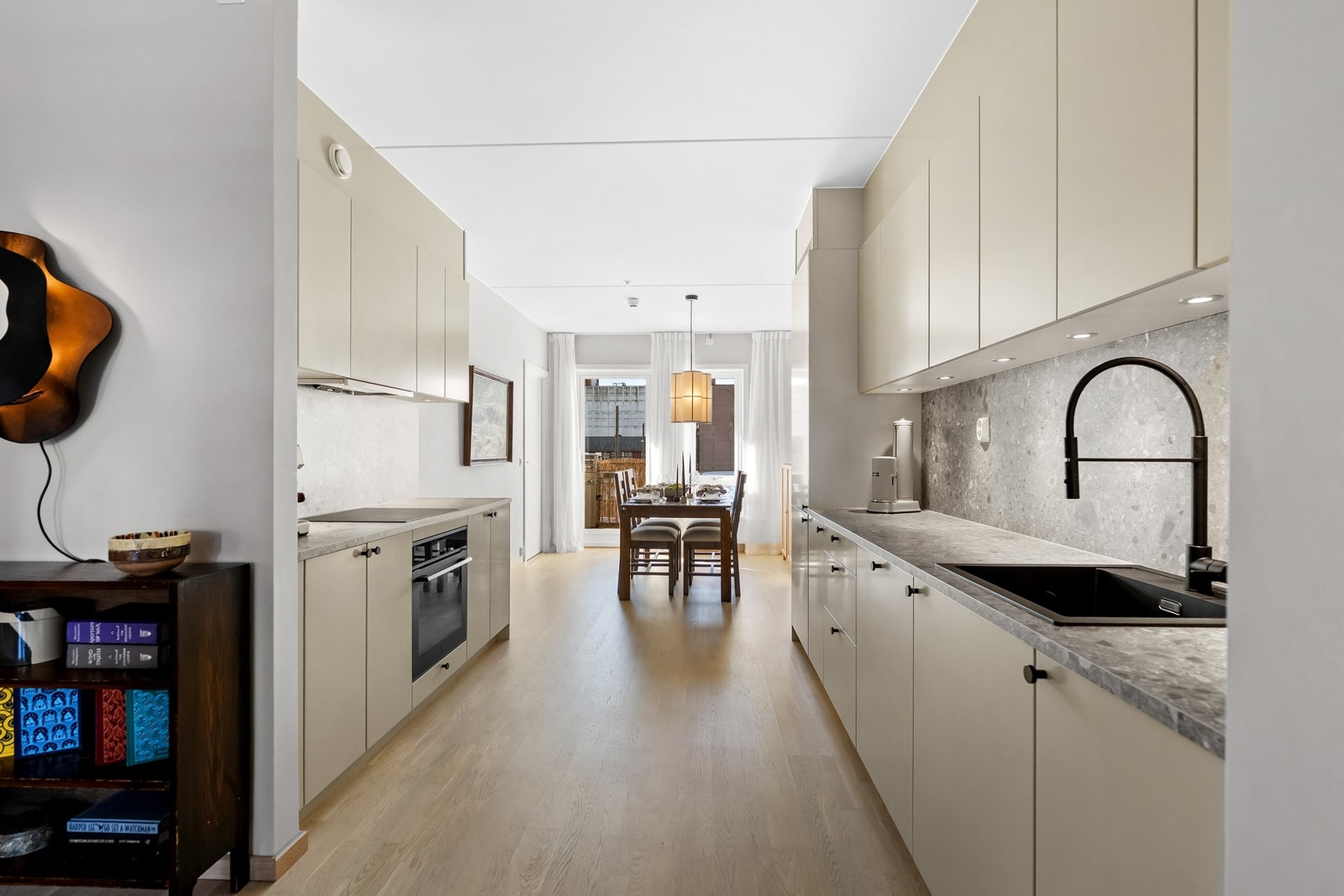 Stilrent kjøkken med glatte fronter og gode arbeidsflater, i åpen løsning mot stuen som skaper en sosial og praktisk oppholdsone. Galleribilde