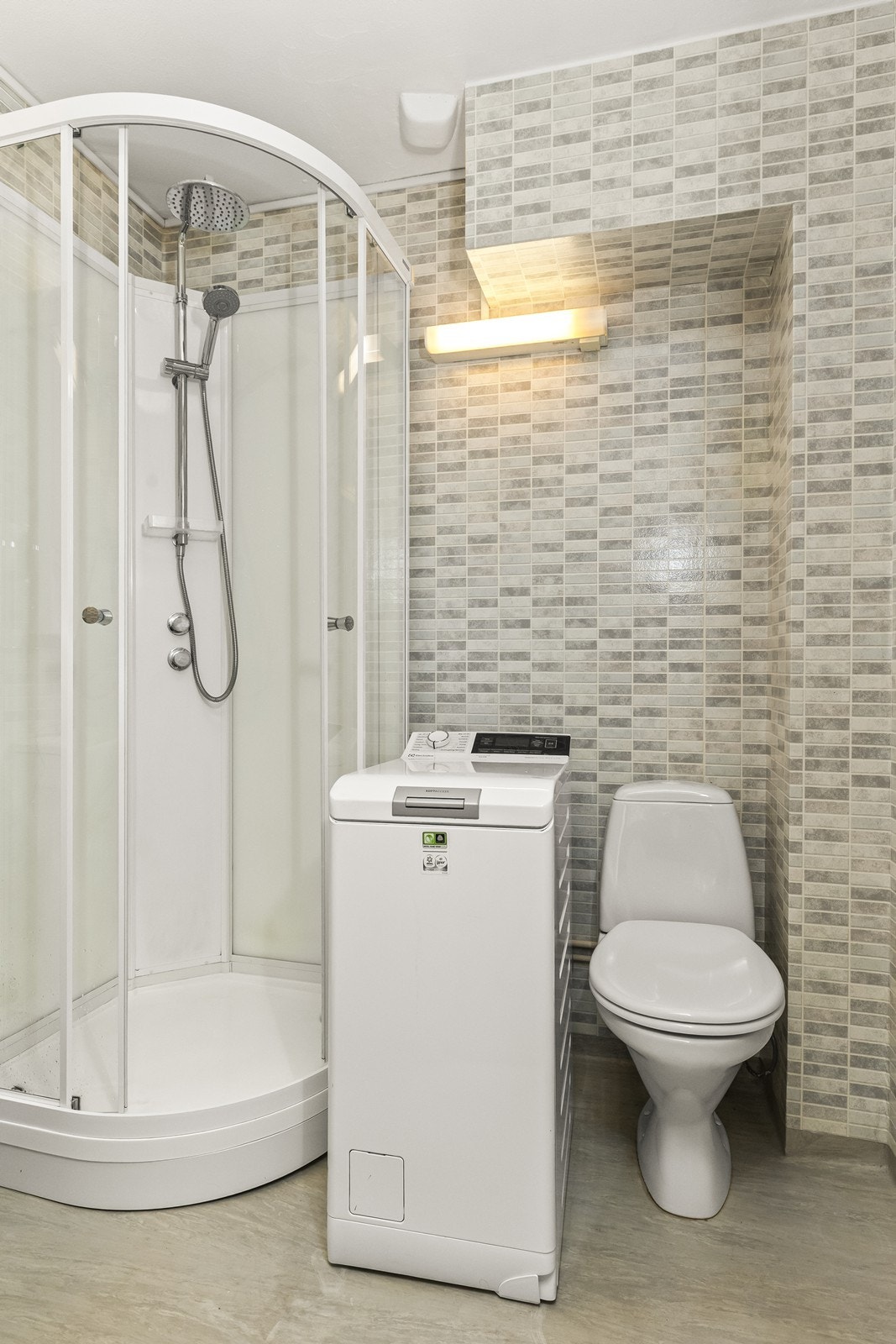 Badet er av eldre dato, men fremstår som funksjonelt og praktisk i hverdagen. Det er installert dusjkabinett og toalett, og rommet har også opplegg for vaskemaskin. Galleribilde