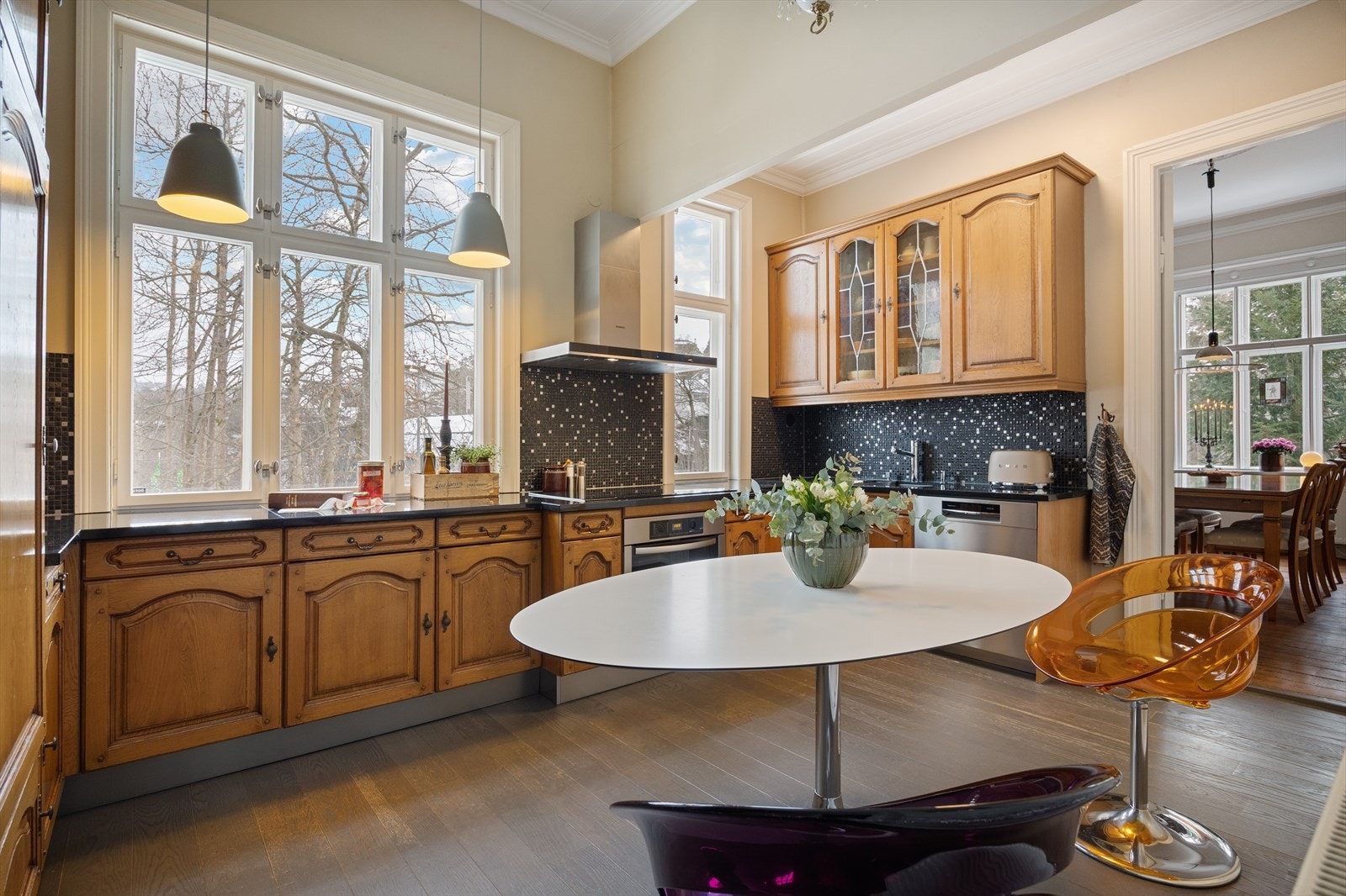 Kjøkkenet fremstår funksjonelt med heltre profilerte fronter, stein benkeplate og integrerte hvitevarer. Løsningen gir fin flyt videre mot spisestuen. Galleribilde