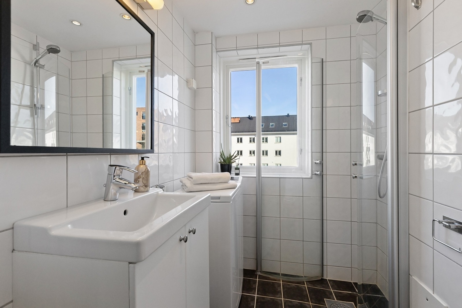 Badet er flislagt med varmekabler - her er det innredet med vaskemaskin, servantskap, speil, toalett og dusj. Galleribilde