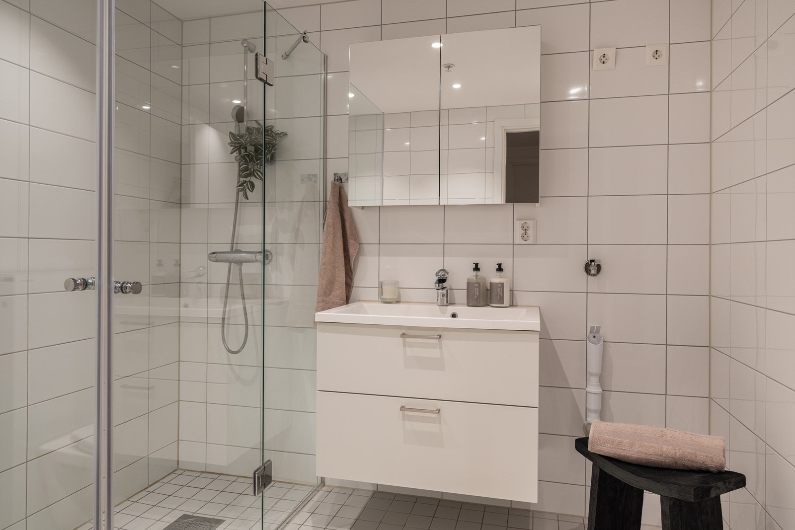 Delikat flislagt bad med moderne innredning, servant og speilskap. Galleribilde