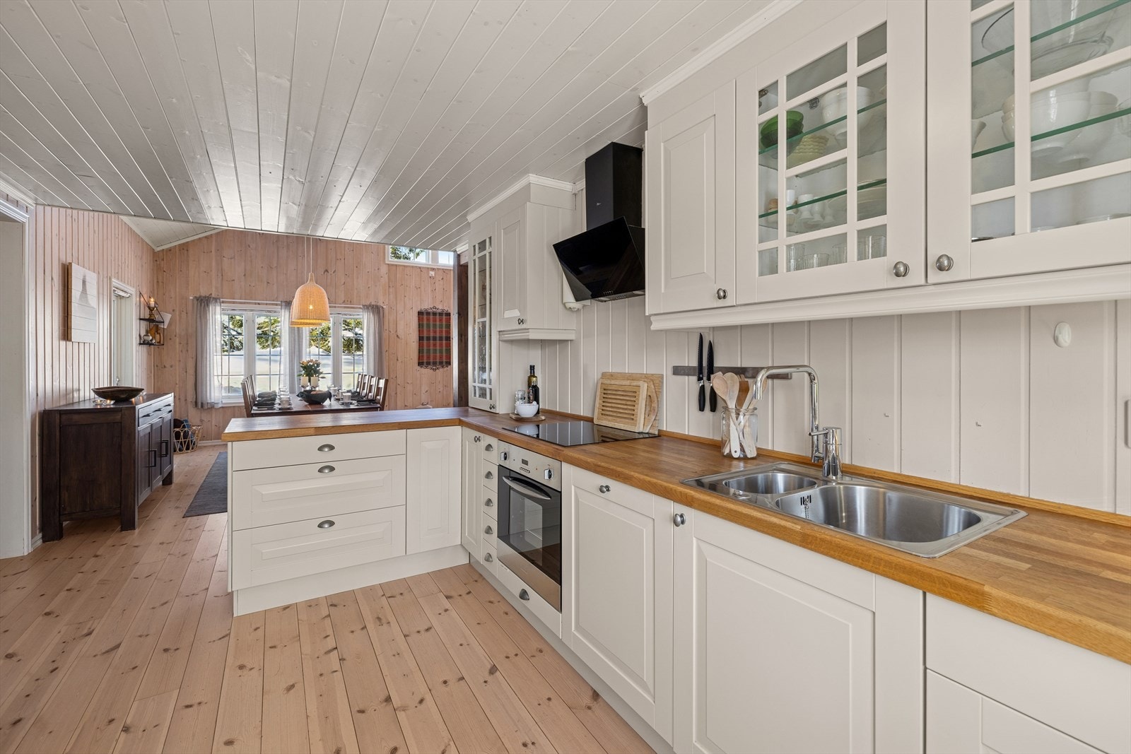 Kjøkkenet har en pen og tidløs innredning med hvite, profilerte fronter og heltre benkeplate med nedfelt kjøkkenkum. Galleribilde