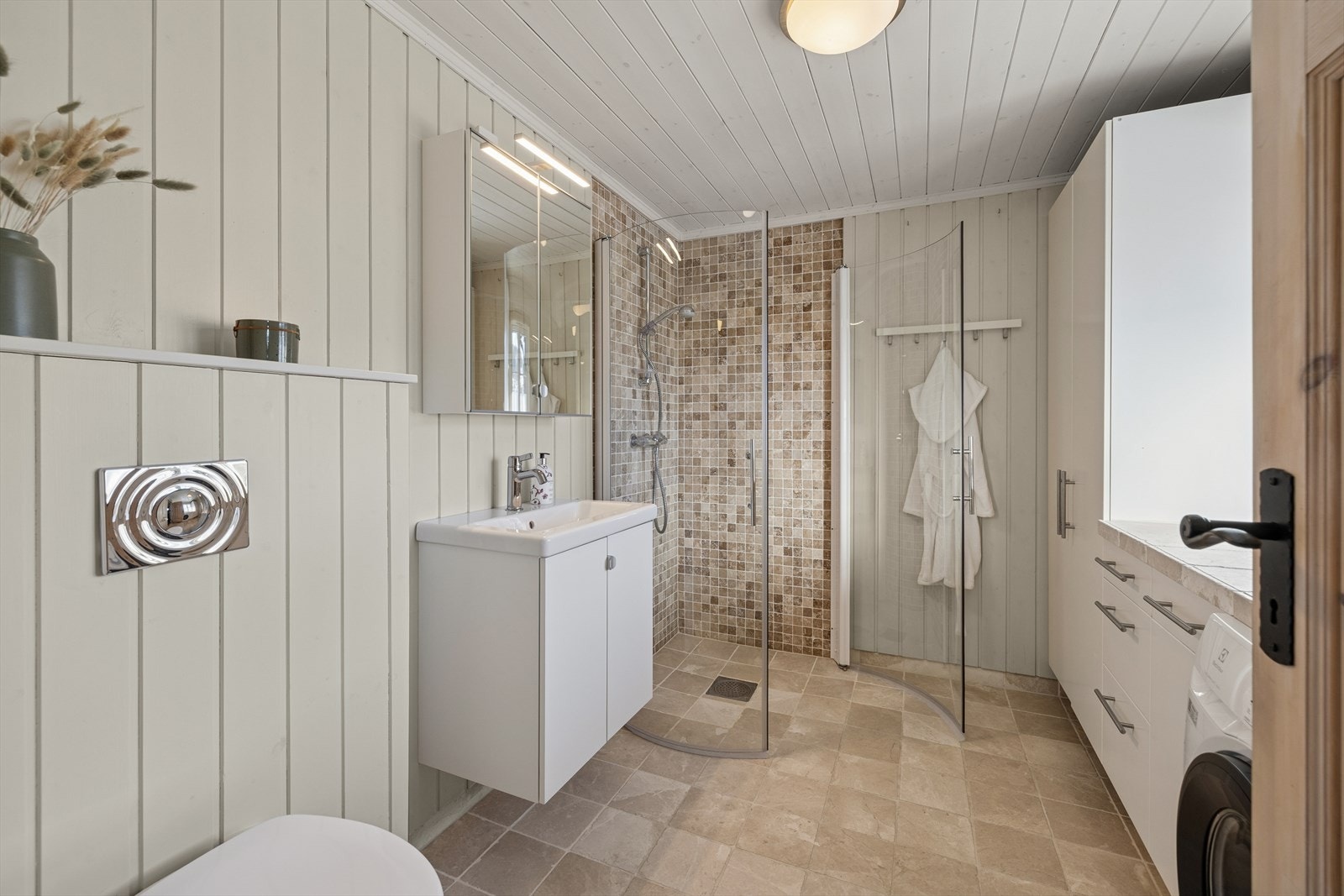 Bad to med fliser på gulvet og en kombinasjon av fliser og panel på veggene. Det er varmekabler i gulvet. Galleribilde