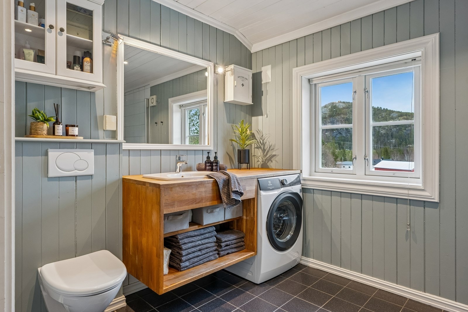 Rommet er innredet med heltre innredning og nedfelt servant, veggmontert toalett og opplegg for vaskemaskin. Dusjsonen har glassdør. Galleribilde