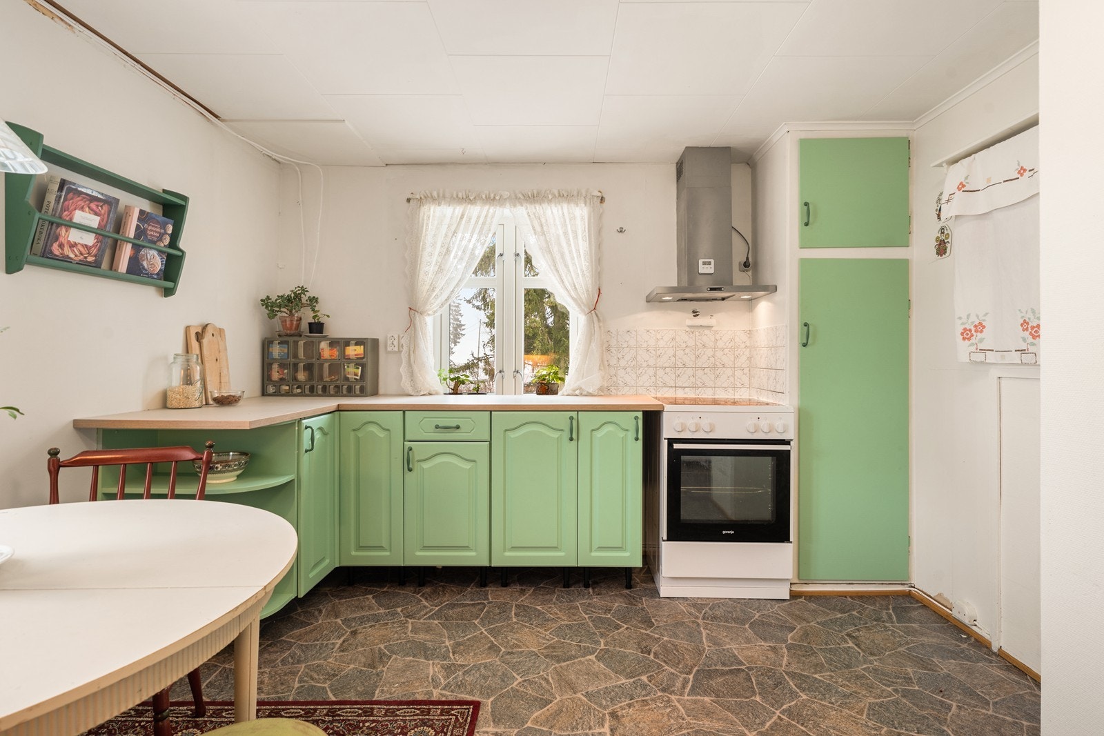 Den mintfargede kjøkkeninnredningen komplementerer husets sjarmerende detaljer og understreker boligens lune og hjemmekoselige atmosfære. Galleribilde