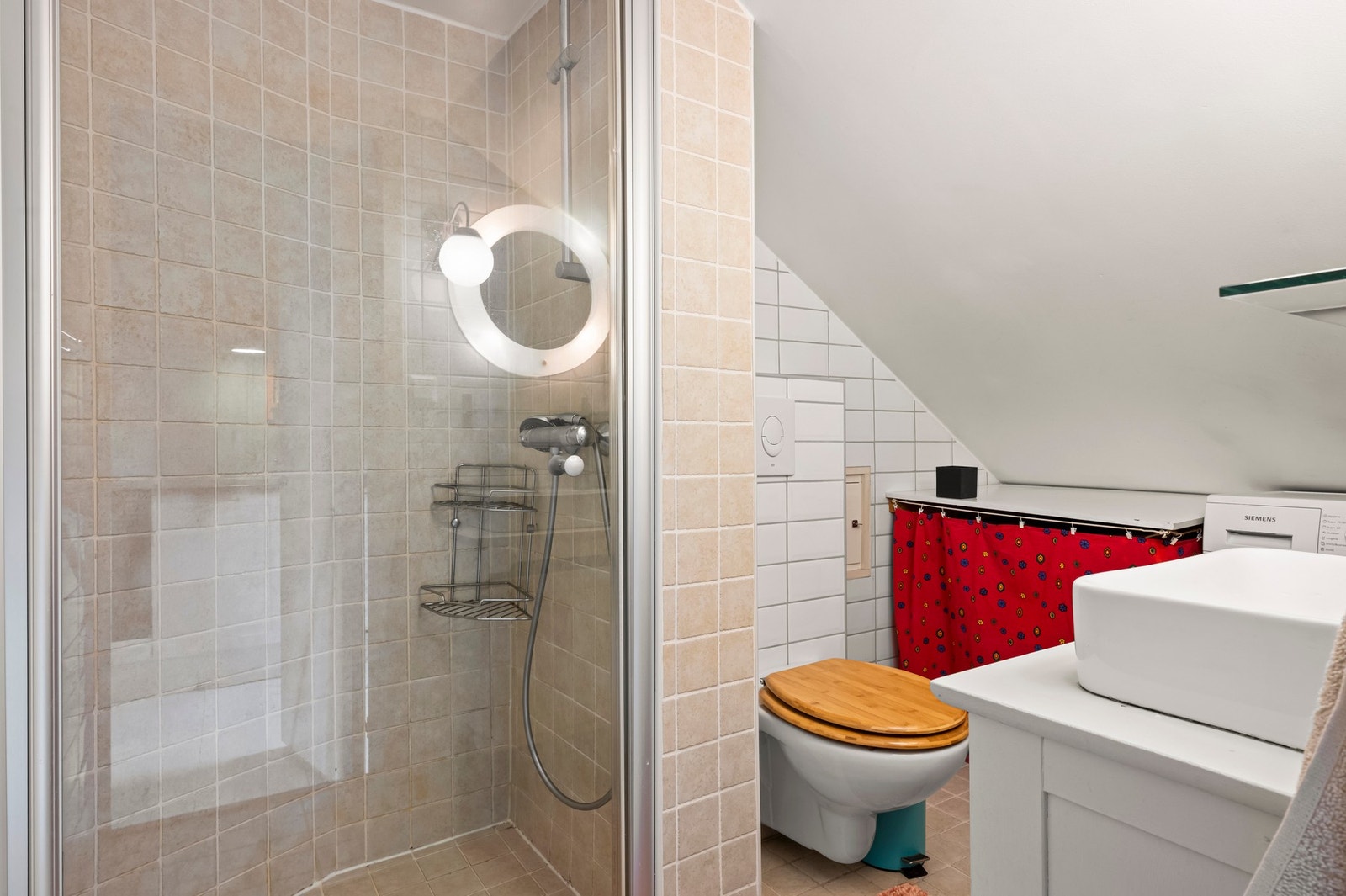 Flislagt bad med servant og dusjnisje med glassdør og dusjarmatur tilkoblet hånddusj Galleribilde