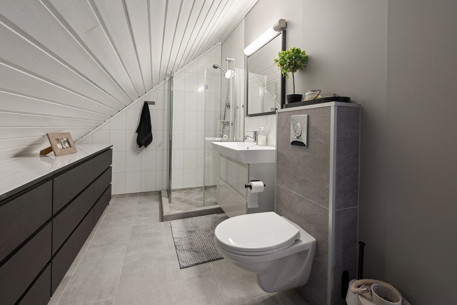 Flislagt bad i 2.etg med veggmontert toalett, servant med innredning og dusjvegger/hjørne Galleribilde