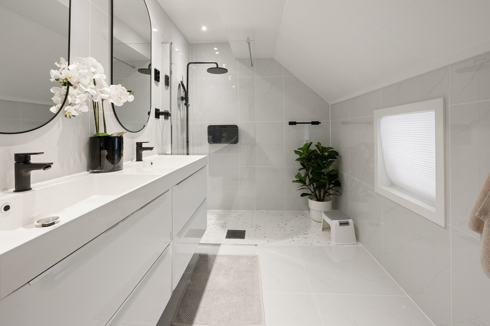 Flislagt bad i 1.etg. med veggmontert toalett, 2 servanter med innredning, dusjvegger/hjørne og gulvvarme Galleribilde