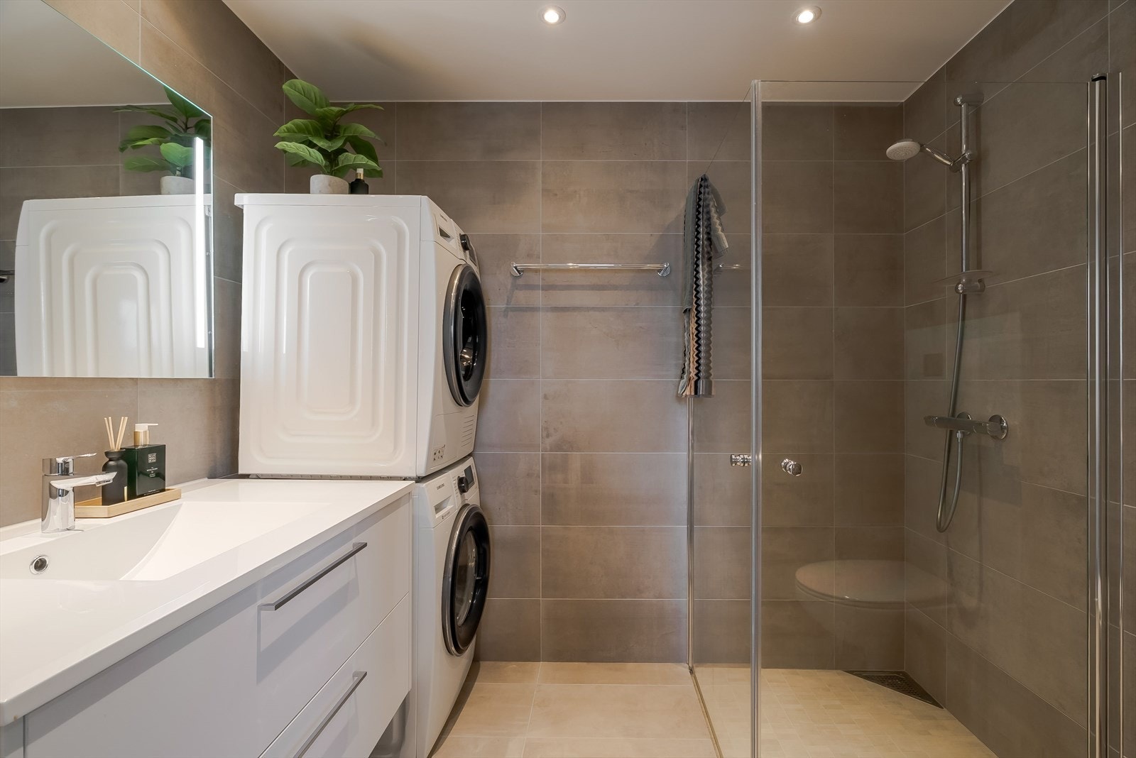 Lekkert baderom utstyrt med stor servantinnredning, speil med lys, toalett, dusjhjørne med innfellbare dusjdører og opplegg for vaskemaskin. Galleribilde