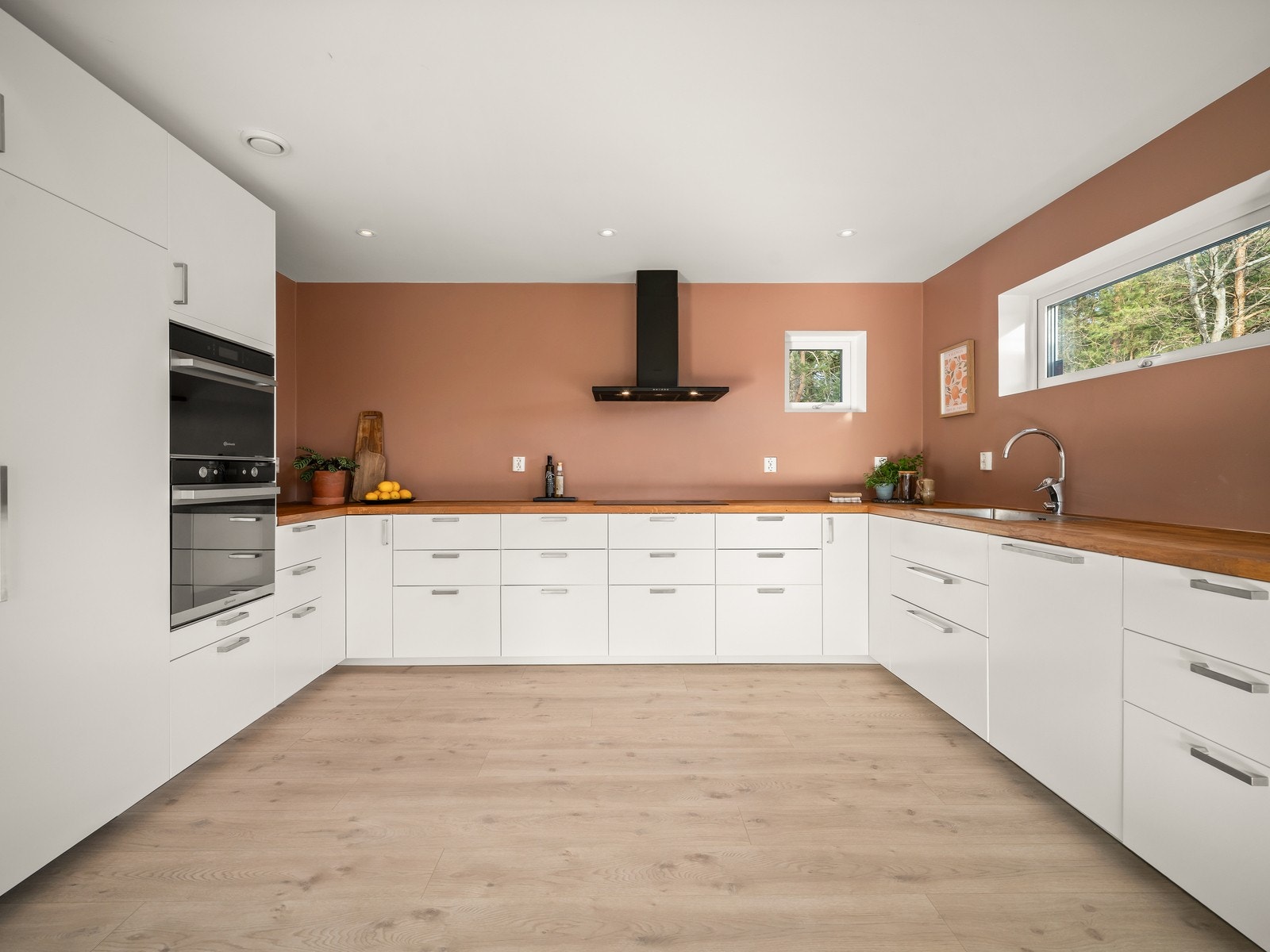 Stilren kjøkkeninnredning fra Ikea med hvite slette fronter, heltre benkeplate og oppvaskkum. Galleribilde