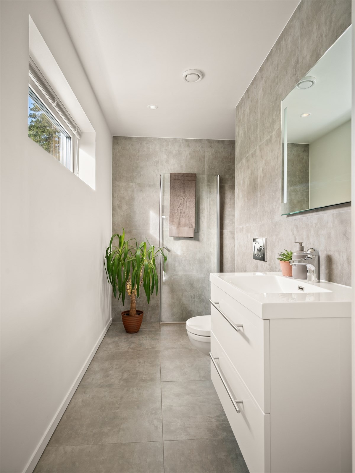 Flislagt baderom i 1.etasje utstyrt med servantinnredning, vegghengt toalett og dusjnisje med glassdør. Galleribilde