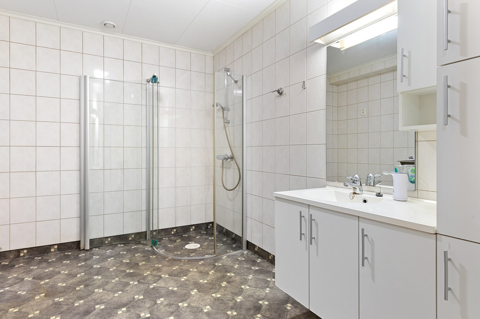 Badet i hovedetasjen har vinylbelegg på gulv med vannbåren varme og flislagte vegger. Galleribilde