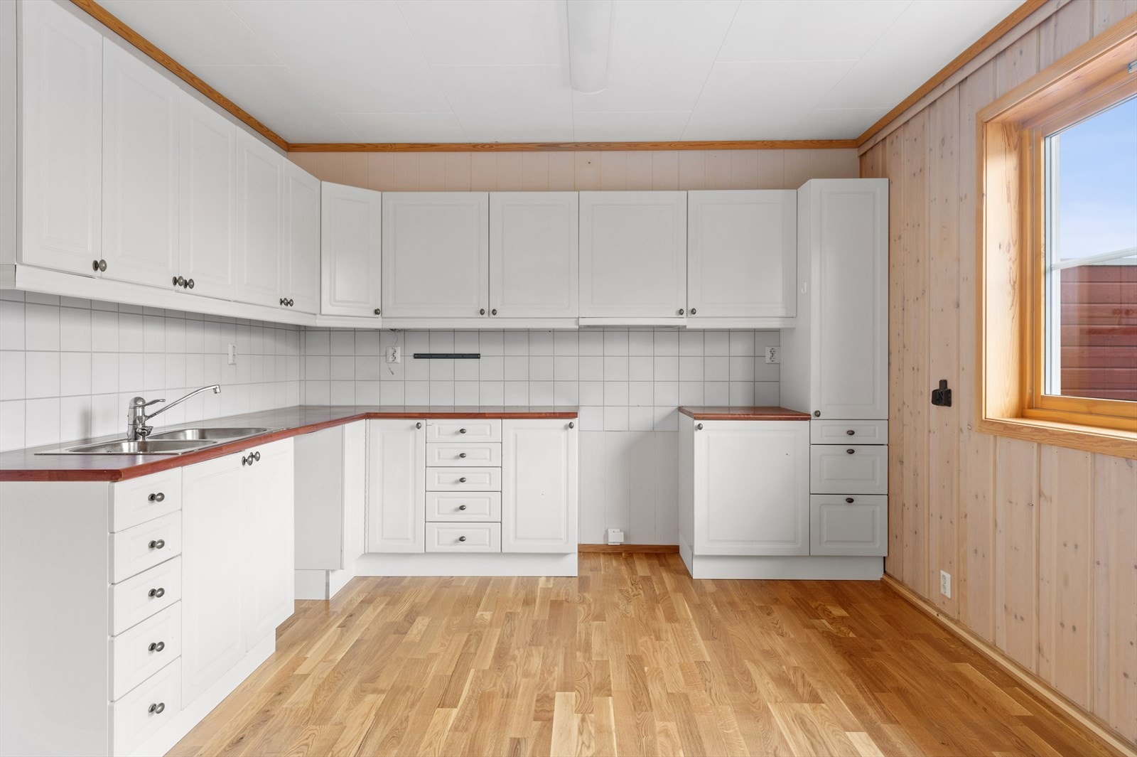 Kjøkkeninnredning med malte profilerte fronter, laminat benkeplate og veggflis over benk. Galleribilde