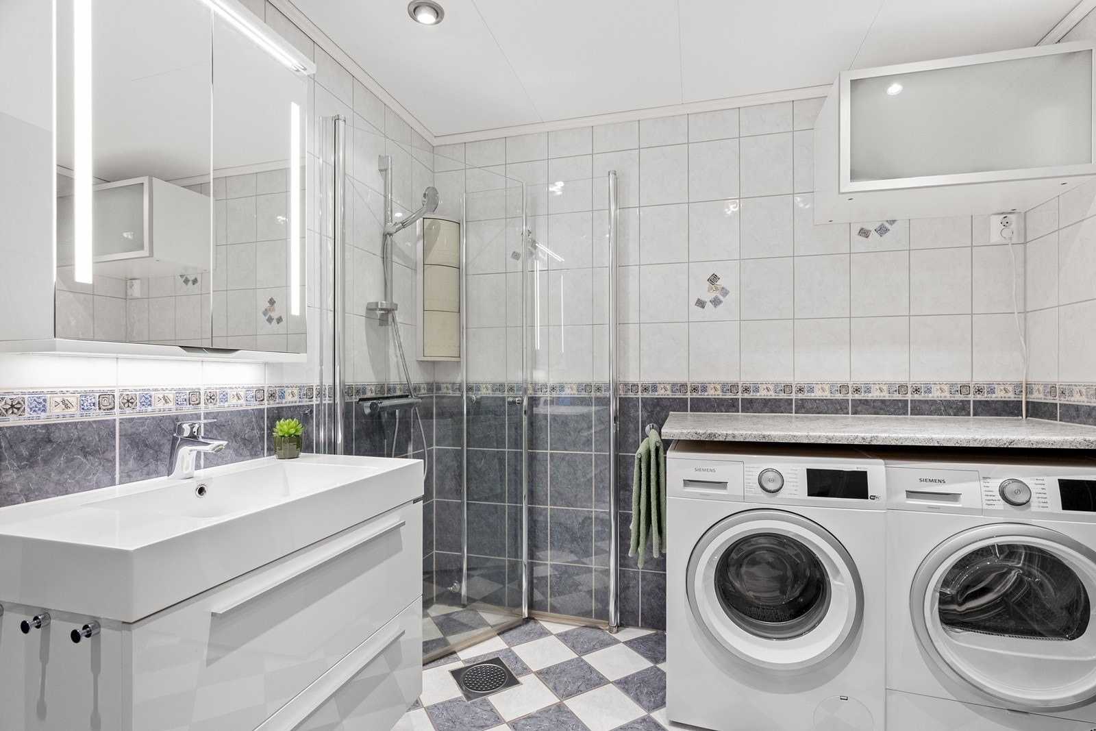 Badet er flislagt og har gulvvarme. Her er det dusjhjørne og praktisk opplegg for vaskemaskin. Galleribilde